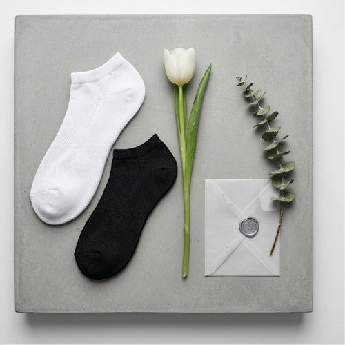 Calcetines deportivos El buen Tin de tejido grueso en colores blanco y negro sobre base de concreto con flor