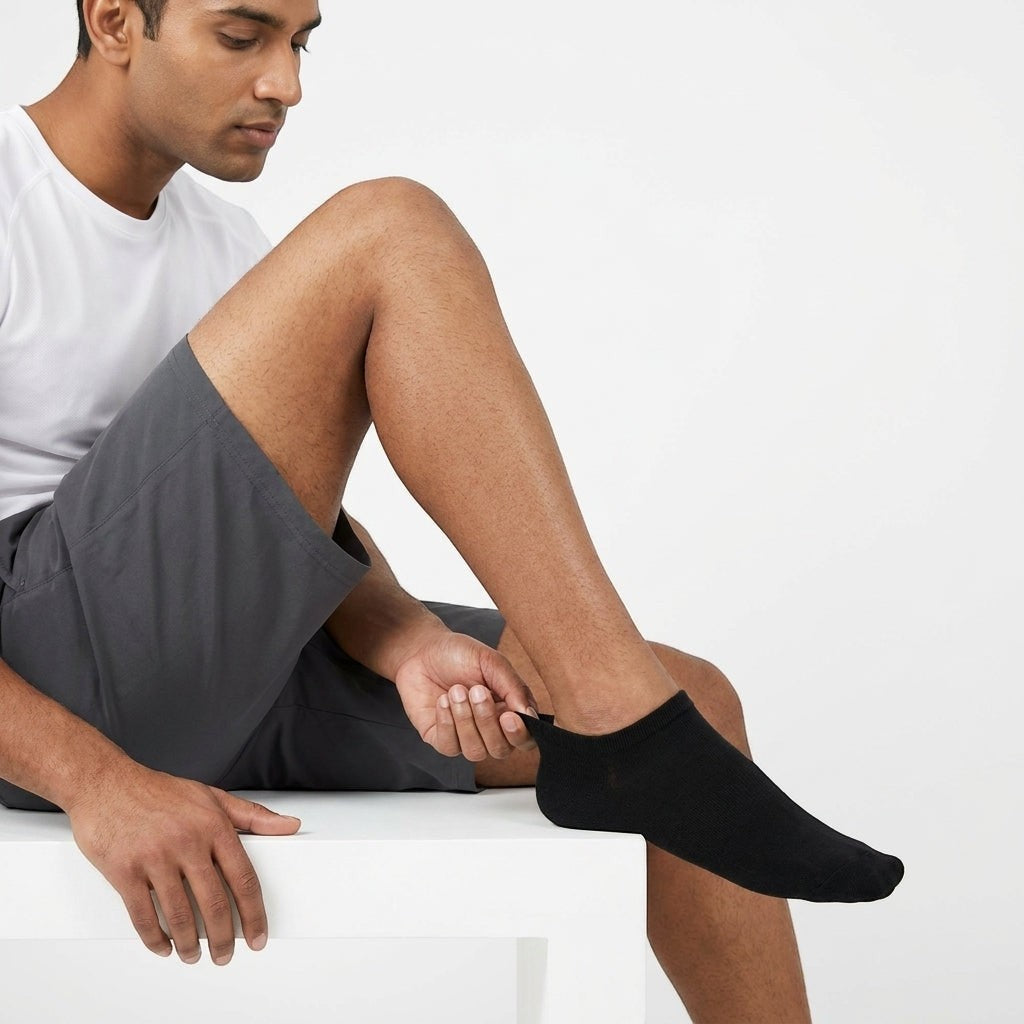 Hombre poniéndose calcetines negros El buen Tin de corte bajo, ideales para uso diario y deportivo.